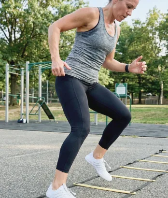 Woman doing agility ladder training in barefoot shoes at an outdoor gym